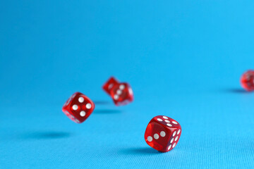 Many red game dices falling on light blue background