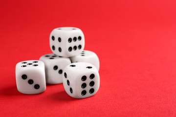 Many white game dices on red background, closeup. Space for text