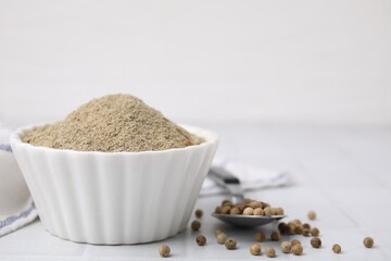 Ground pepper and peppercorns on white tiled table. Space for text