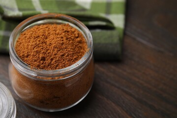 Ground red pepper in jar on wooden table, closeup. Space for text