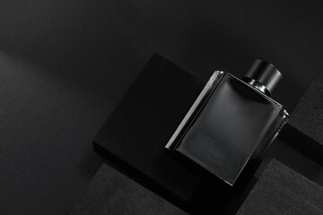 Stylish presentation of luxury men`s perfume in bottle on black background, top view. space for text
