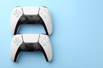 Wireless game controllers on light blue background, flat lay. Space for text