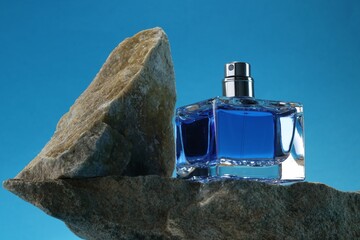 Stylish presentation of luxury men`s perfume on stones against light blue background