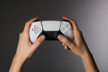 Woman using game controller on grey background, closeup