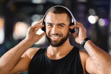 A man with a beard is wearing headphones, listening to music or audio. He appears focused or...