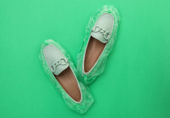 Women's mules in shoe covers on green background, top view