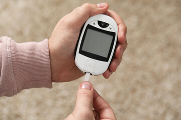 Diabetes test. Man with glucometer on blurred background, closeup