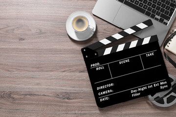 Flat lay composition with movie clapper and film reel on wooden table, space for text