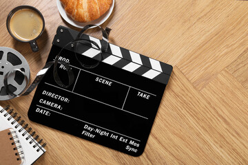 Flat lay composition with movie clapper on wooden table, space for text