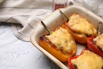 Delicious stuffed bell peppers in baking dish on white textured table, closeup