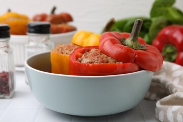 Delicious stuffed bell peppers on white tiled table, closeup