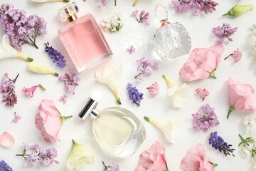 Luxury perfumes and floral decor on white background, flat lay