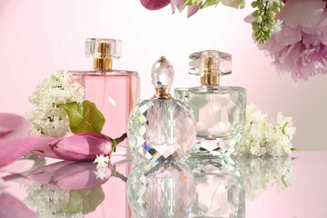 Luxury perfumes and floral decor on mirror surface against pink background