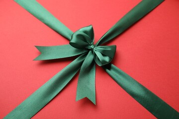 Green satin ribbon with bow on red background