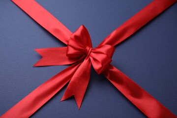 Red satin ribbon with bow on blue background