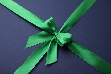 Green satin ribbon with bow on blue background