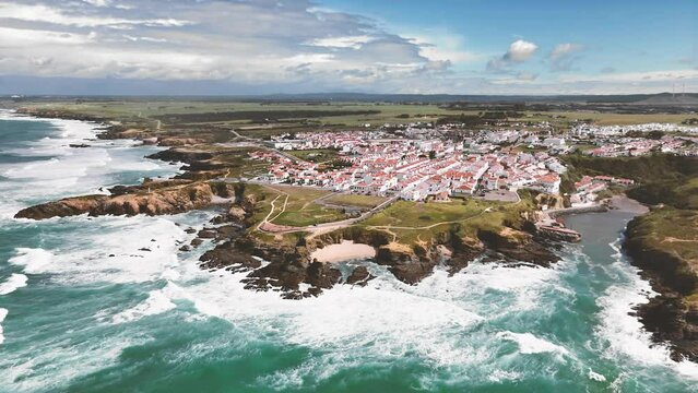 Drone flight towards Porto Covo in the west of Portugal. View of the coastline and village with traditional houses