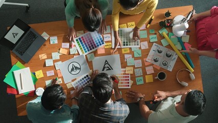 Top down aerial view of designer looking at logo while project manager choosing color palettes....