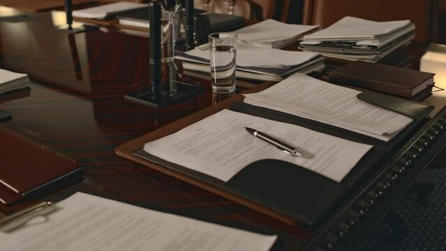 No people footage of lots of documents and legal paperwork on wooden conference table in empty boardroom at legal firm
