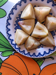 Abiu fruit cut into pieces on white porcelain plate with blue details