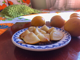 Abiu fruit cut into pieces on white porcelain plate with blue details