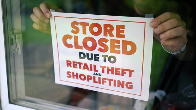 A small business owner places a CLOSED sign on the front door or window. Shoplifting and retail theft has become a problem in large cities across America with an influx of immigration.  	
