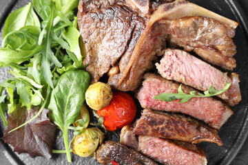 Delicious grilled beef meat, vegetables and greens on board, top view