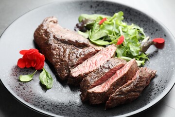 Pieces of delicious grilled beef meat and greens on table, closeup