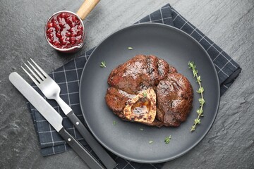 Delicious roasted beef meat served with sauce on black table, flat lay