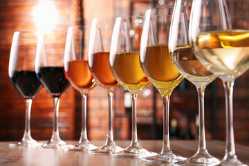 Different tasty wines in glasses on wooden table