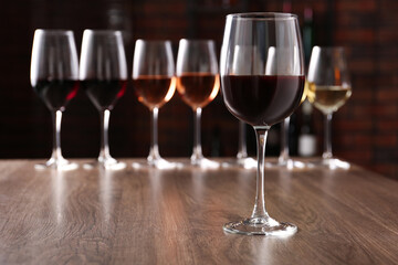 Different tasty wines in glasses on wooden table