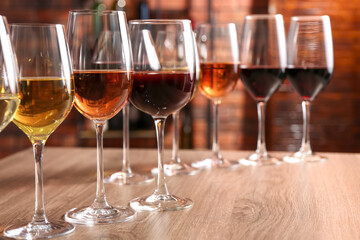 Different tasty wines in glasses on wooden table, space for text