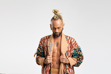 Obraz premium African-american guy wearing vibrant stylish jacket posing isolated on white background. Looking down with serious face young millennial man with perfect abdominal muscle