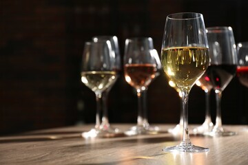 Different tasty wines in glasses on wooden table, space for text