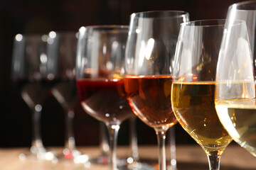 Different tasty wines in glasses against blurred background, closeup