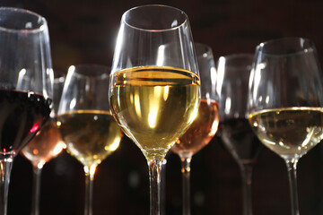 Different tasty wines in glasses against blurred background, low angle view
