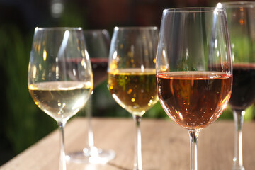 Different tasty wines in glasses on wooden table