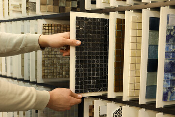 Man choosing tile among different samples in store, closeup