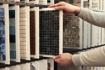 Man choosing tile among different samples in store, closeup