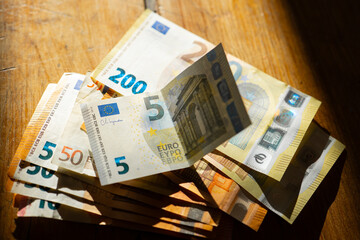 Euro Money on a wooden table in a strip of light.Income in European countries. Euro currency...