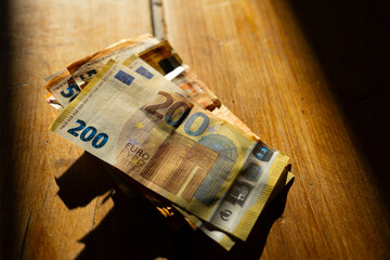 euro bills on a wooden table in a strip of light.Income in European countries. Euro currency...