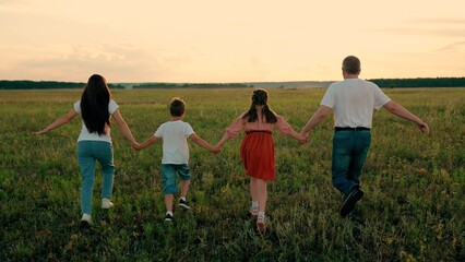 Happy children with father and mother playing on green meadow at sunset. Happy family, Children...