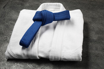 Fototapeta premium Blue karate belt and white kimono on gray background