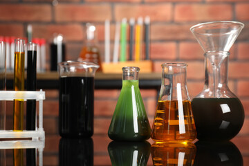 Laboratory glassware with different types of oil on mirror table indoors, closeup