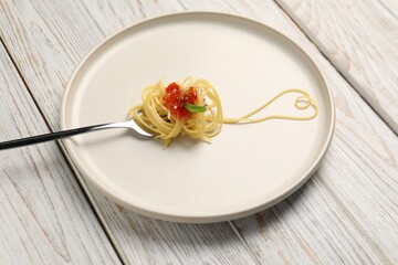 Heart made with spaghetti and fork on white wooden table