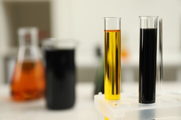 Test tubes with different types of crude oil against blurred background, closeup. Space for text