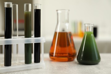 Laboratory glassware with different types of crude oil on light grey table