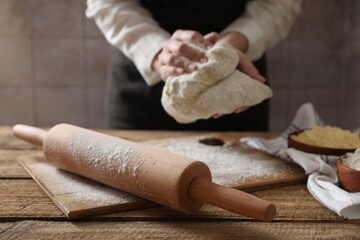 Woman making dough at wooden table, selective focus