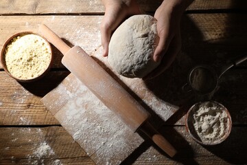 Man making dough at wooden table, top view