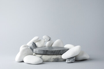 Presentation for product. Stone podium and pebbles on light grey background. Space for text